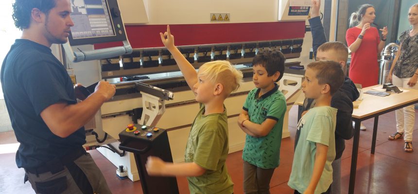 De kinderen van de lagere school helpen mee aan de machine in de technische school
